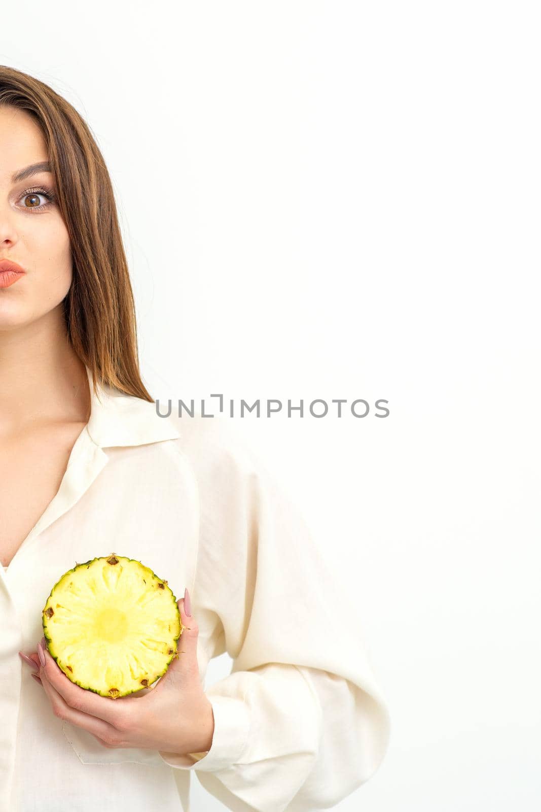 Young Caucasian smiling woman holding slices pineapple over white background, breast health concept