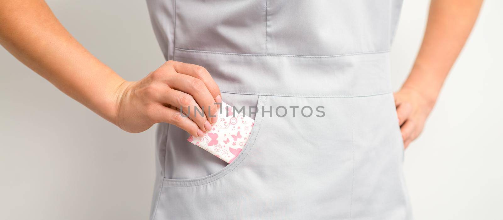 The female hand puts menstrual sanitary pads into her pocket, close up. by okskukuruza