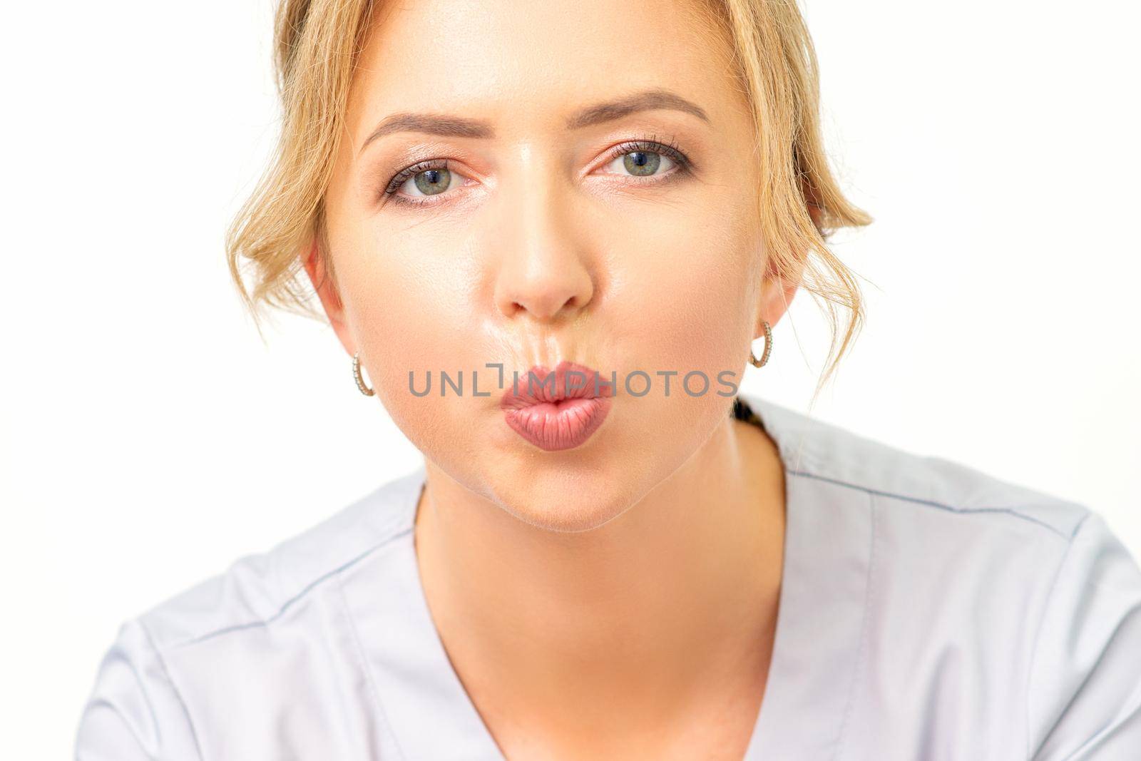 Young attractive woman doctor giving kiss over white background, closeup