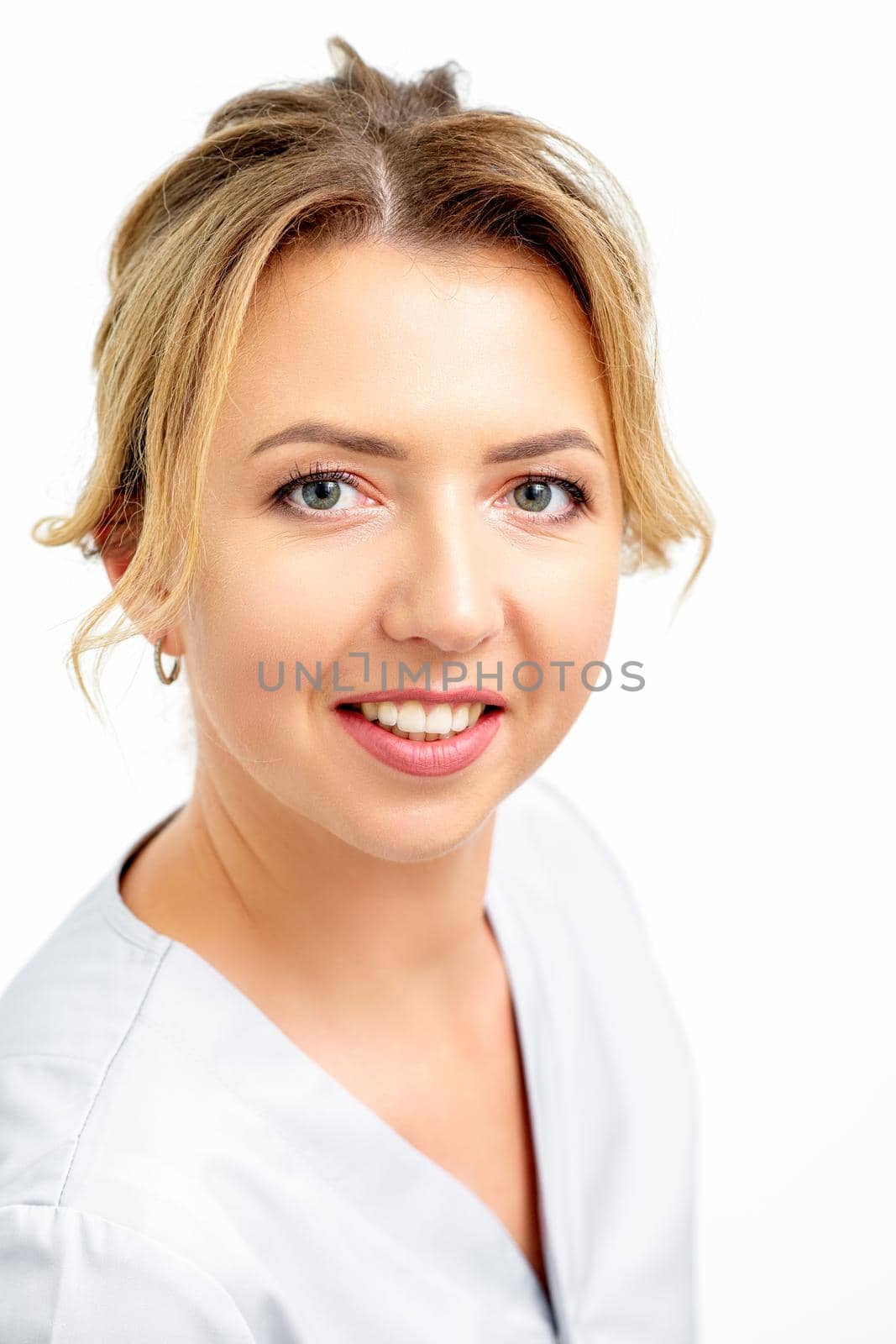 Close-up portrait of young smiling female caucasian healthcare worker standing staring at the camera on white background. by okskukuruza
