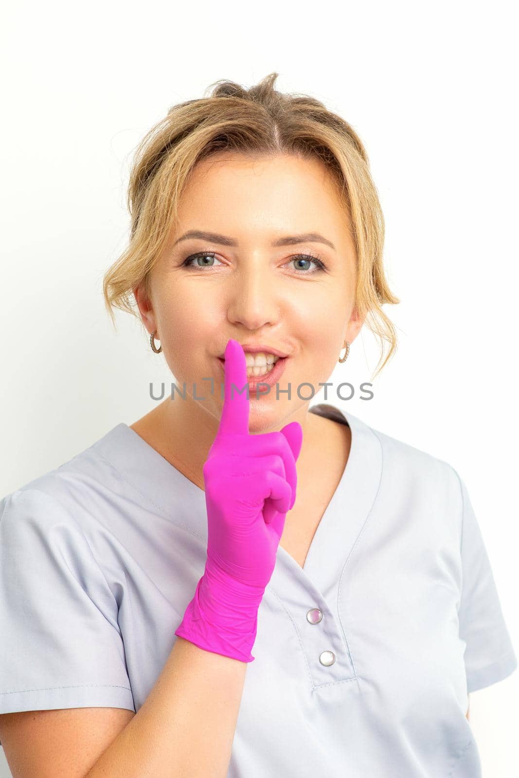 Young beautiful caucasian woman doctor, beautician doing silent gesture pressing his index finger to his lips isolated on white background