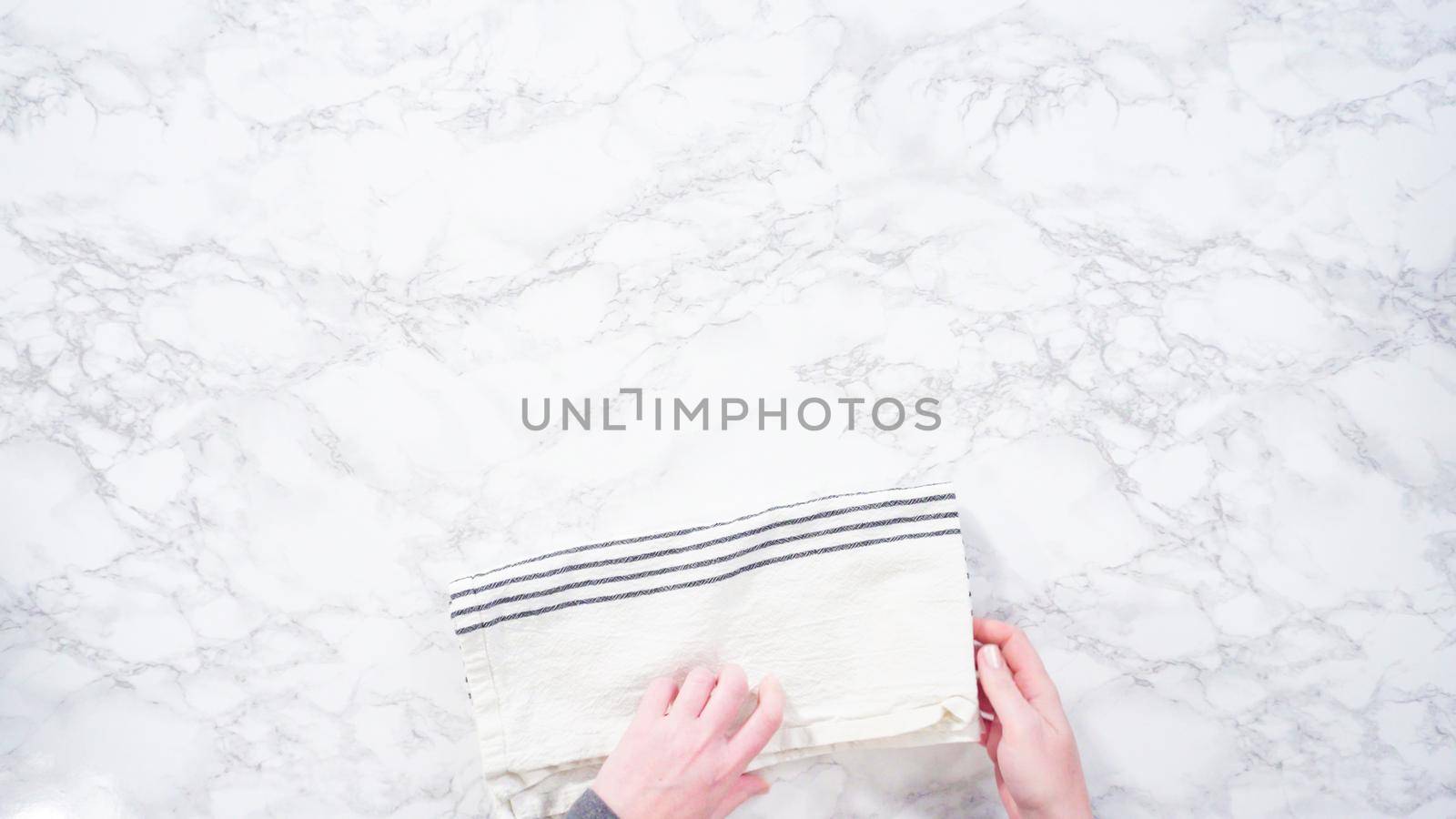 Flat lay. Step by step. Folding clean kitchen towel on a marble surface.
