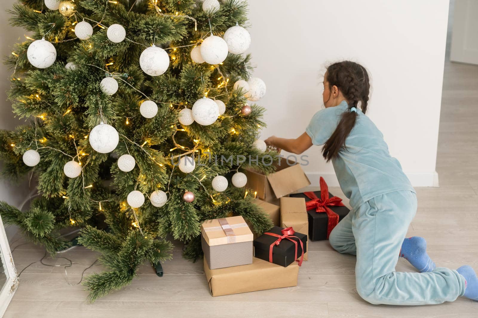 little child girl is decorating the Christmas tree indoors. The morning before Xmas by Andelov13