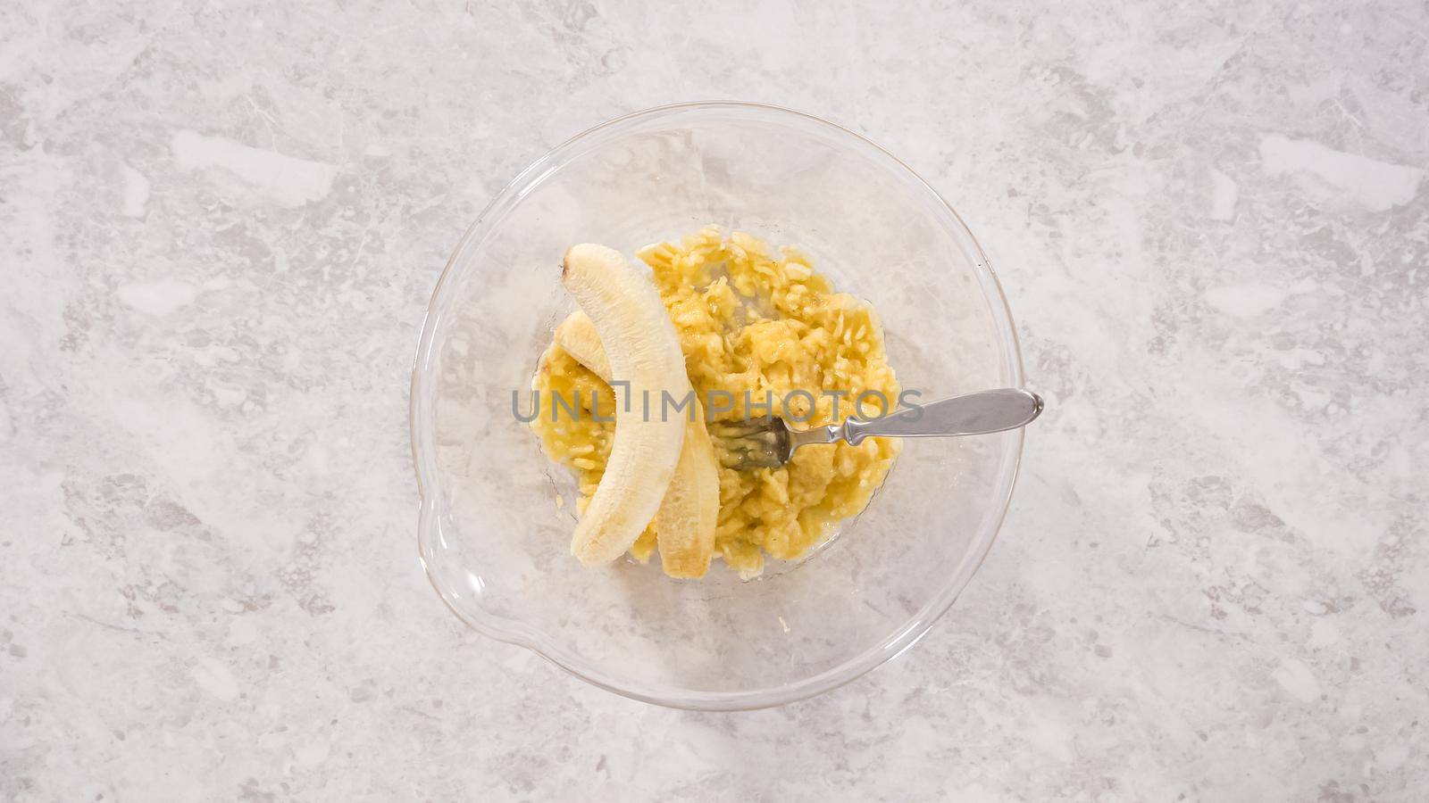 Flat lay. Step by step. Smashing riped bananas in a glass mixing bowl to prepare coconut banana pancakes.