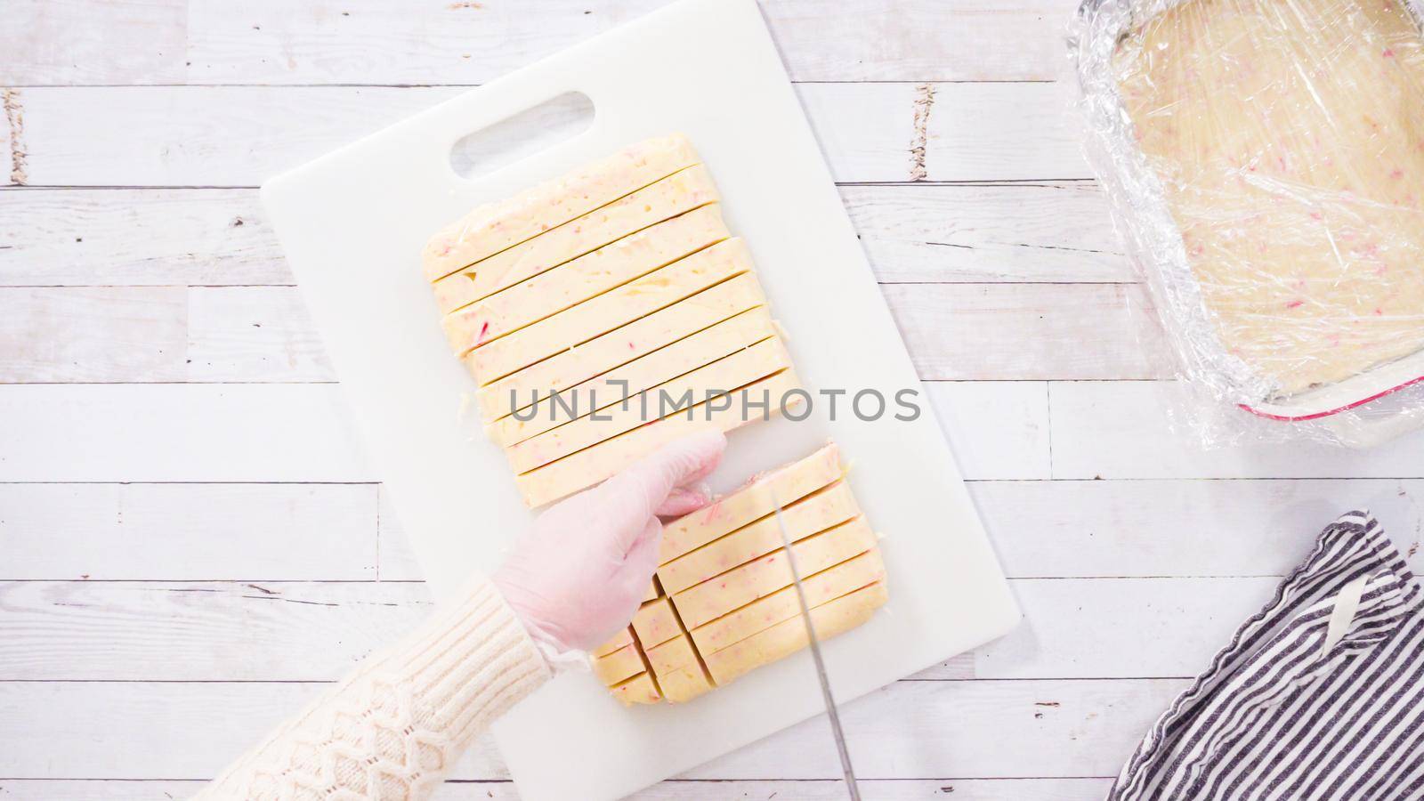 Flat lay. Step by step. Cutting homemade candy cane fudge on a white cutting board.