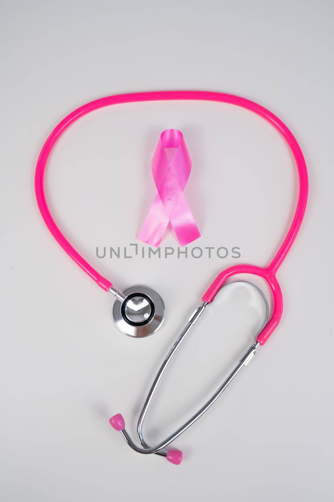 Pink ribbon and stethoscope on a white background. The concept of the fight against breast cancer. by mrwed54