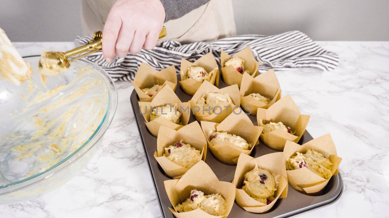 Step by step. Scooping dough into tulip muffin liners with mixture scoop to bake cranberry muffins.