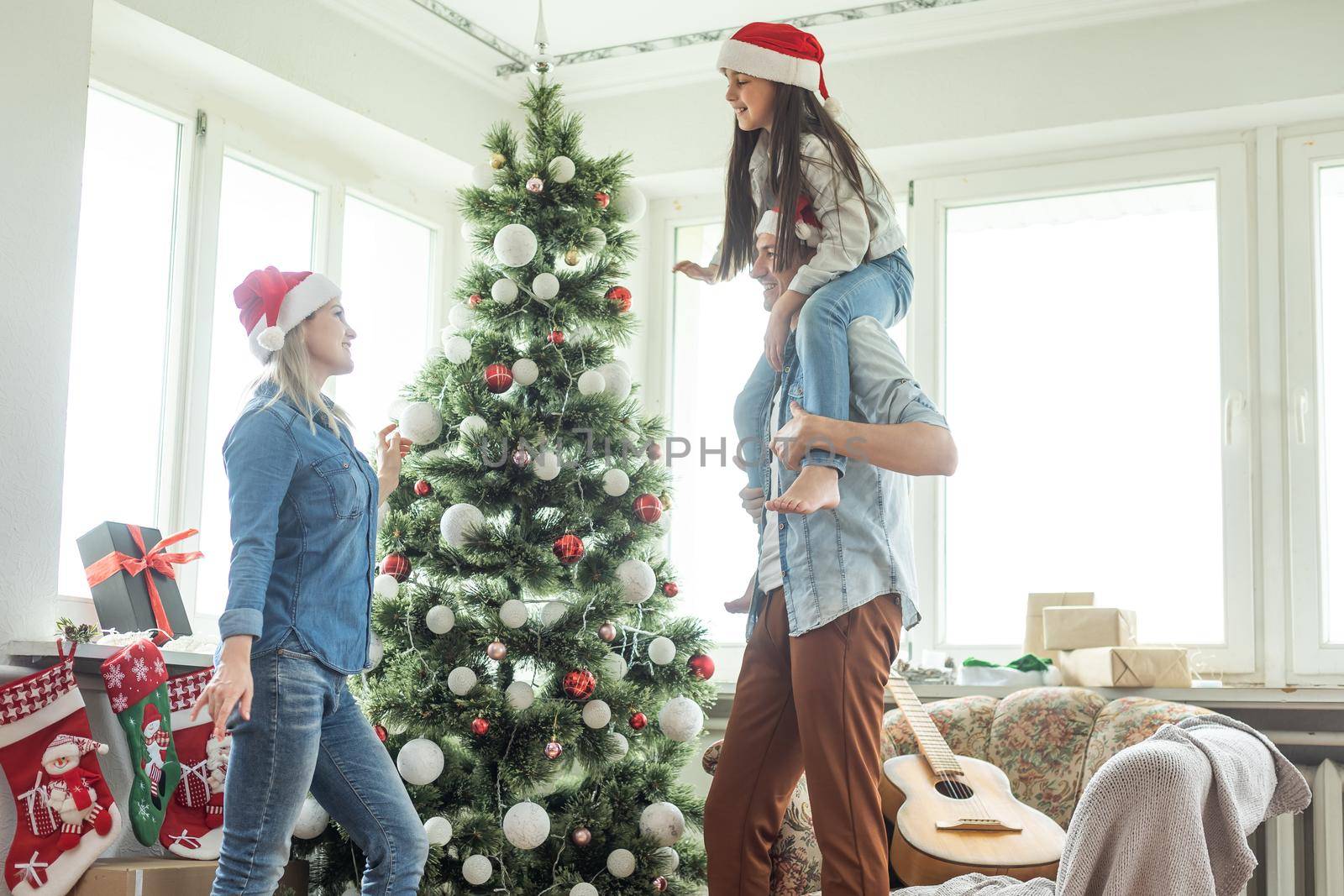 family having fun and playing together near Christmas tree indoors