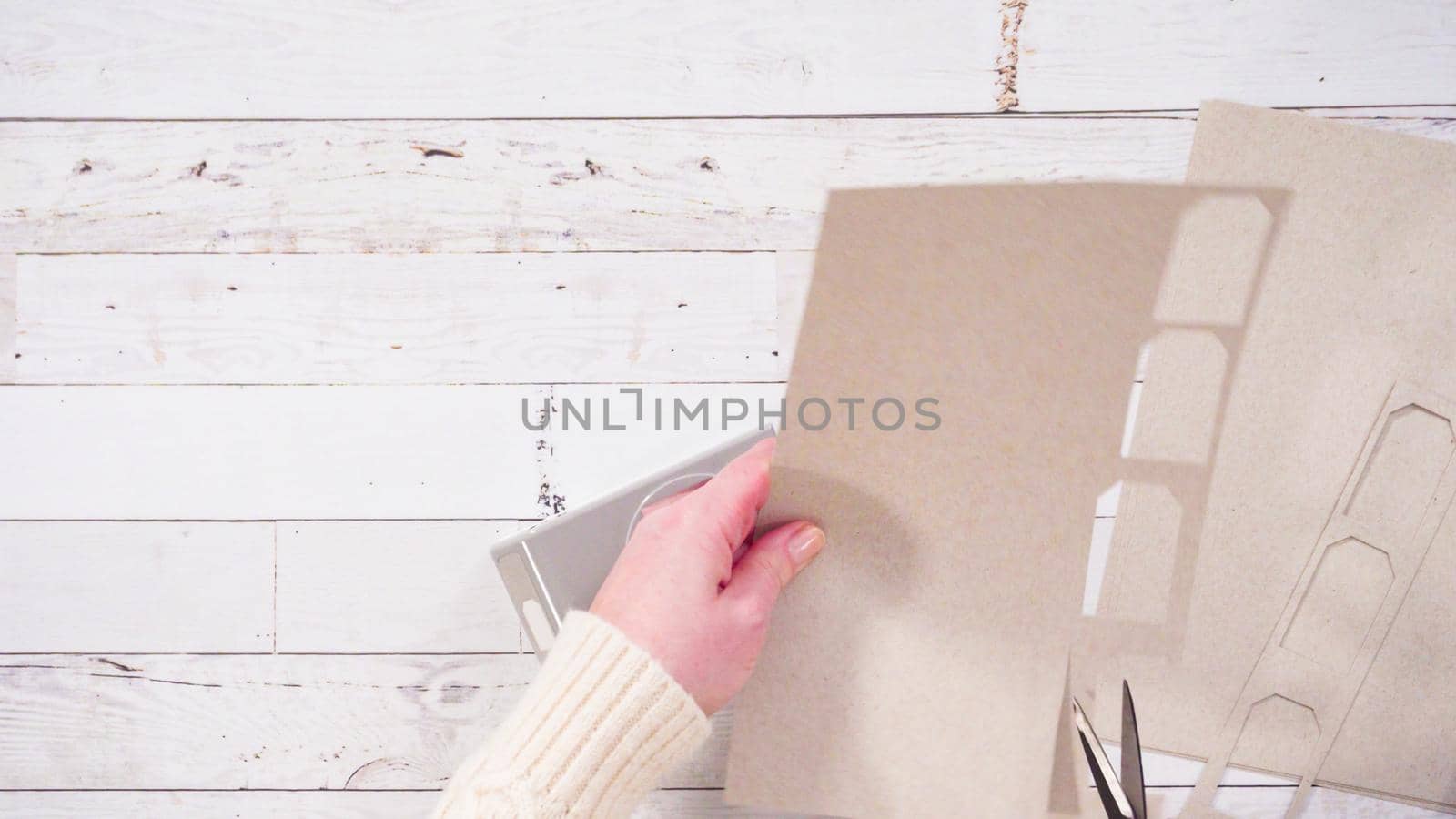 Flat lay. Step by step. Cutting out gift tags from brown paper with a paper punch.