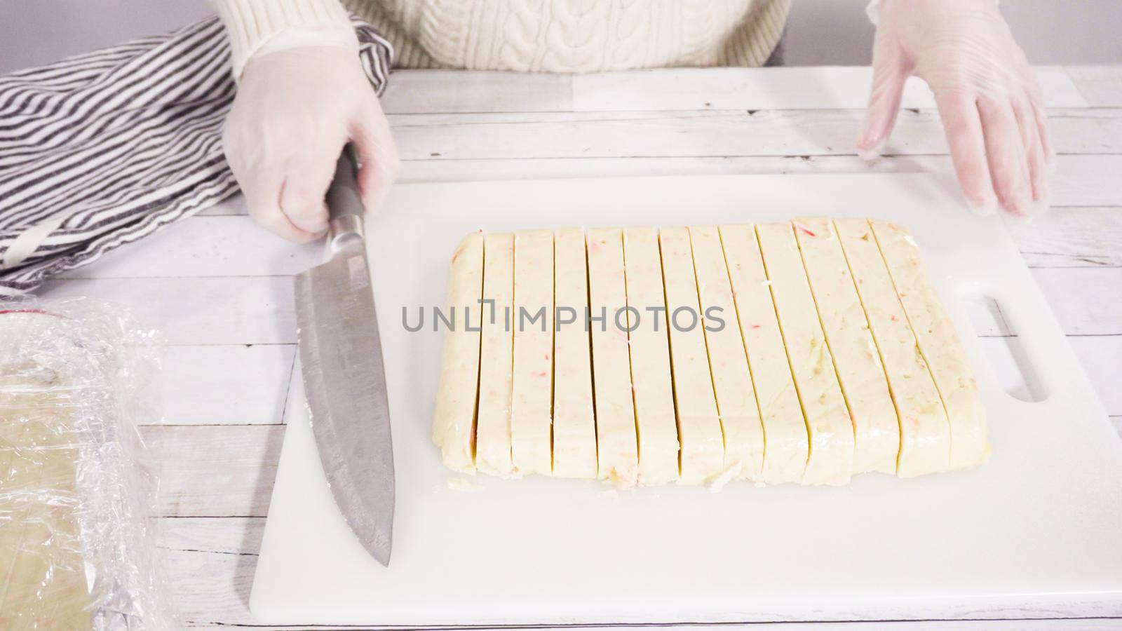 Step by step. Cutting homemade candy cane fudge on a white cutting board.