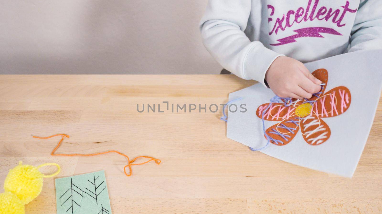 Little girl learning how to sew with sewing craft kit for kids.