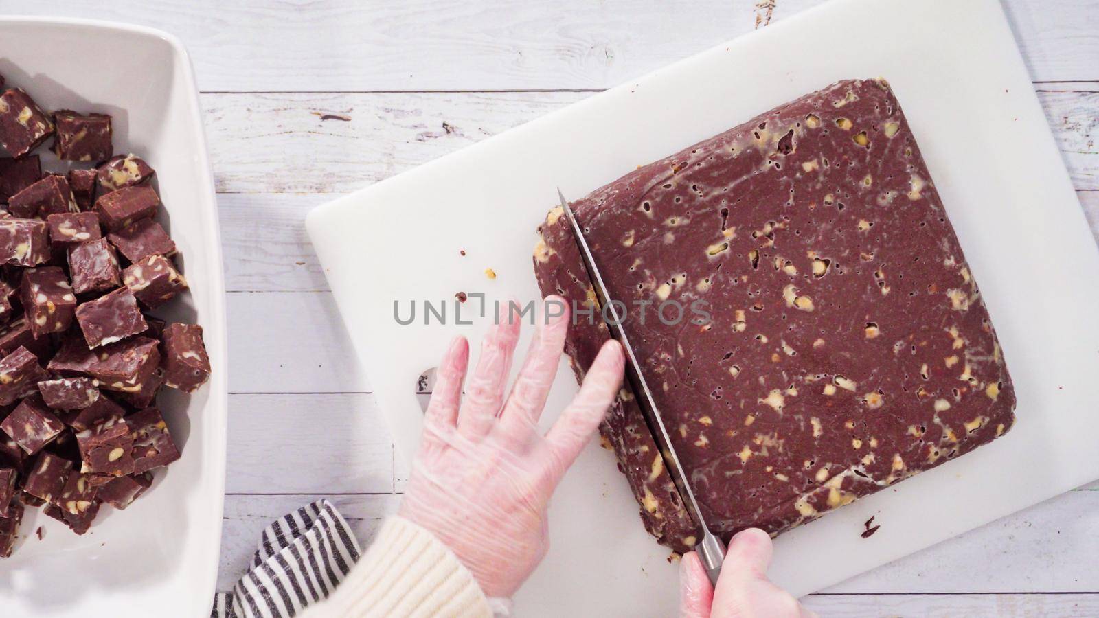 Flat lay. Step by step. Cutting homemade macadamia fudge on a white cutting board.