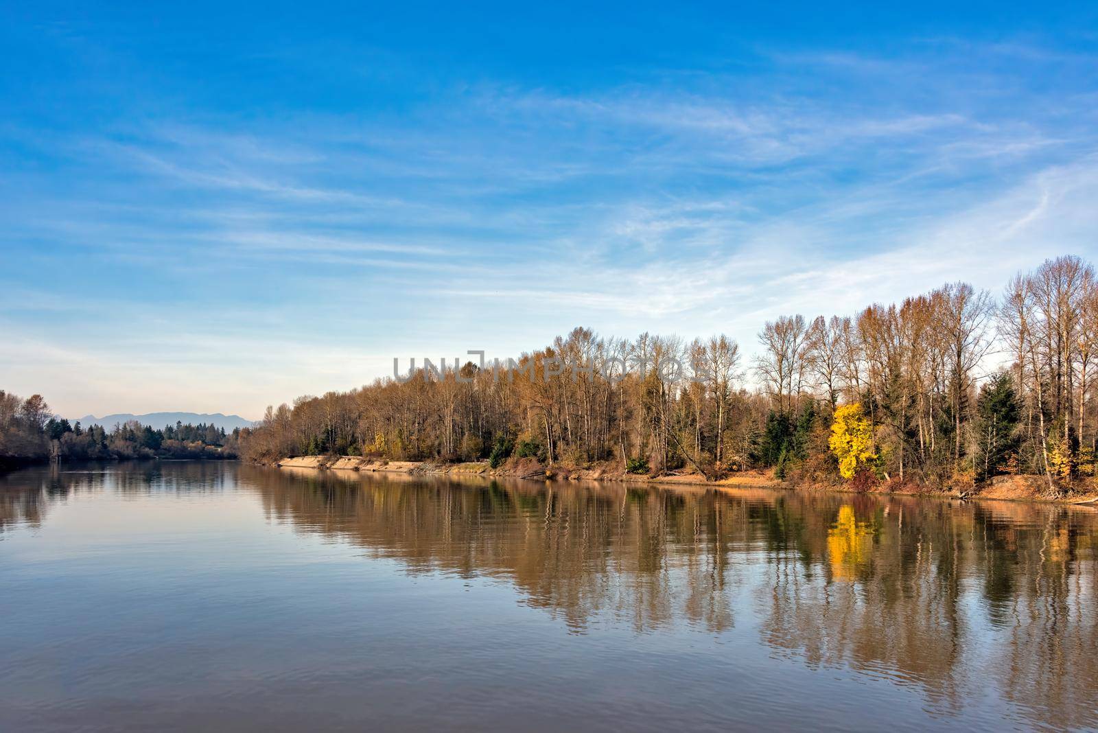 Autumn landscape with a river on blue sky background.