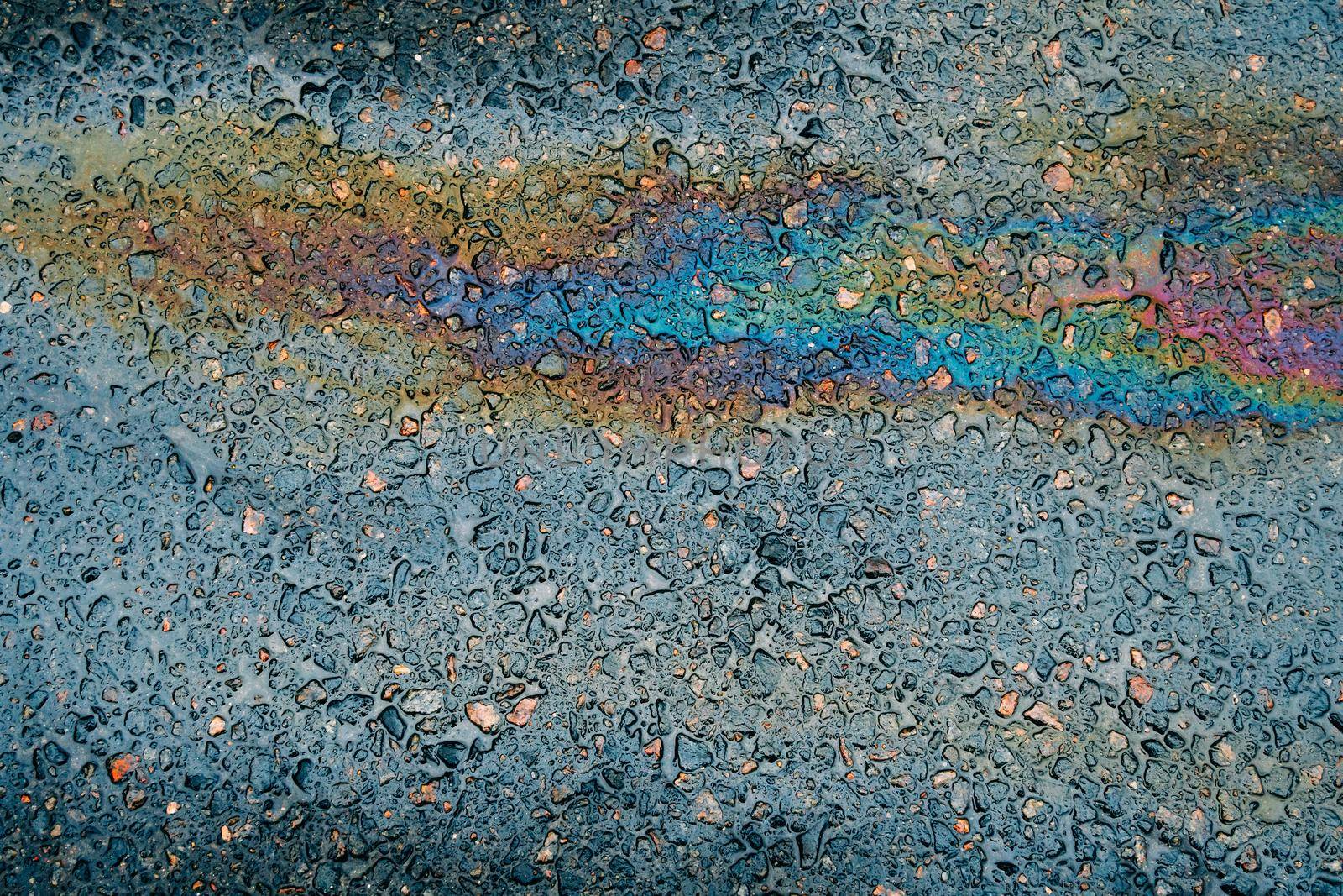 Multi colored oil spill on asphalt road, abstract background
