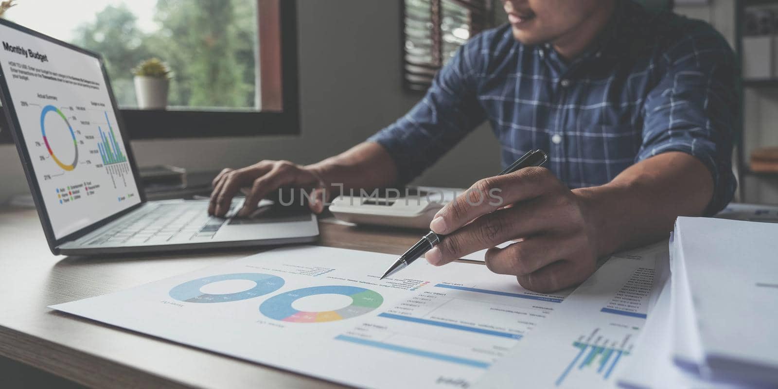 Young businessman writing business plan at desk in modern office. Planning analyze investment, business strategy and marketing, using graph chart and digital tablet..