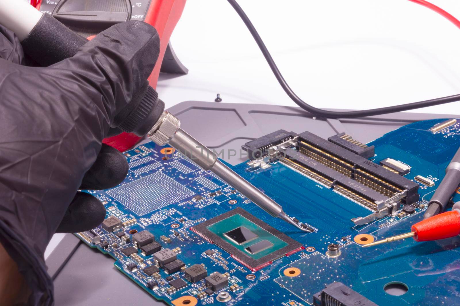 Repairing laptop motherboard. Soldering electronic component on pcb.