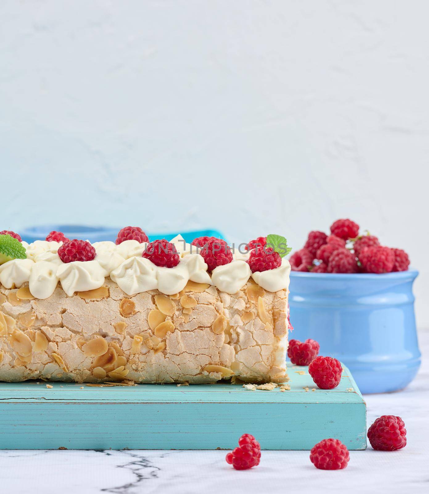 Baked meringue roll with cream and fresh red raspberry, white background	