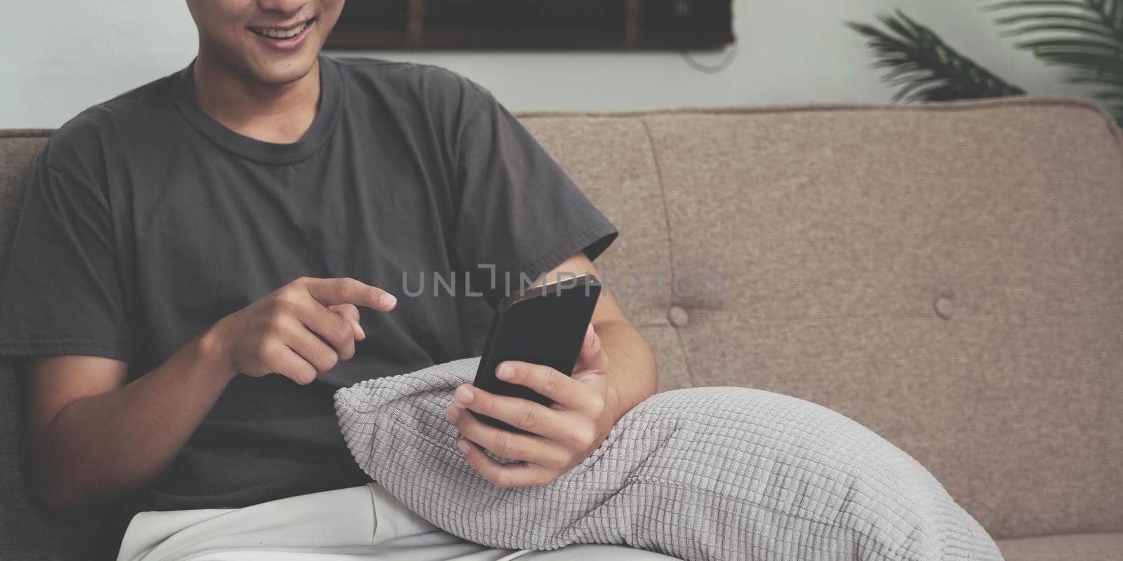 Close up hand of man using smartphone at home by wichayada