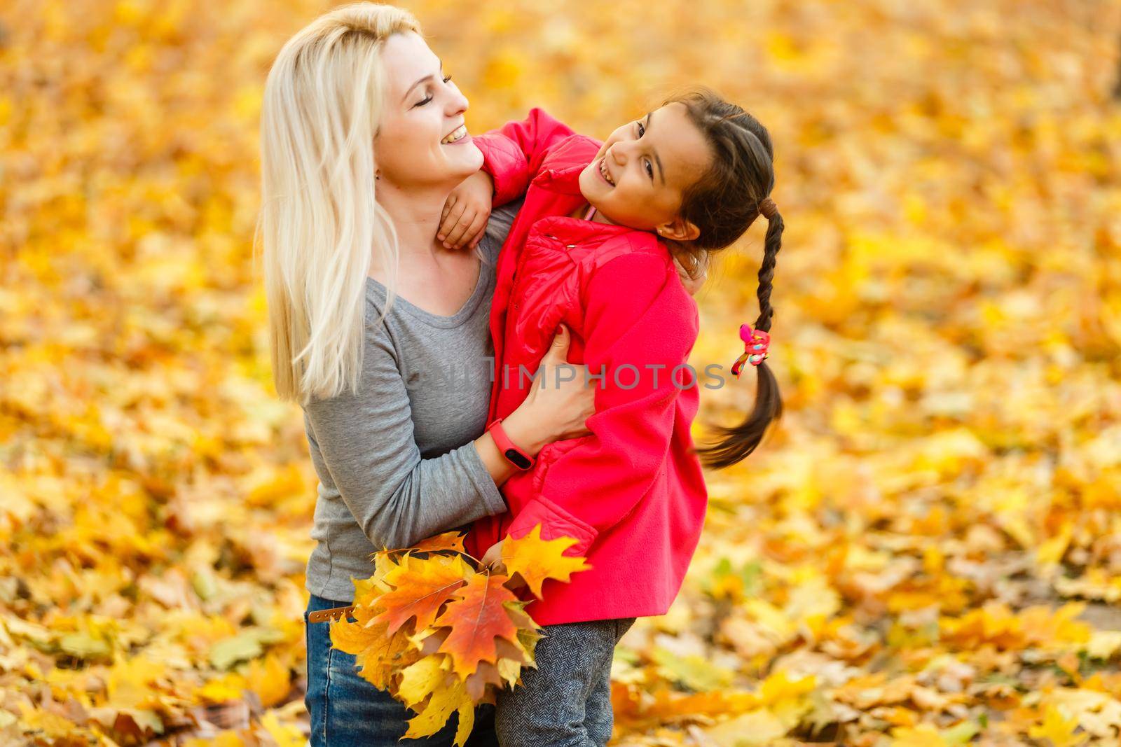 mother and daughter in the city park in autumn having fun time