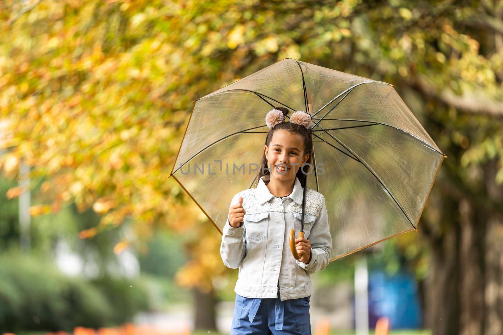 Kid playing out in the rain. Children with umbrella play outdoors in rain. autumn weather. by Andelov13