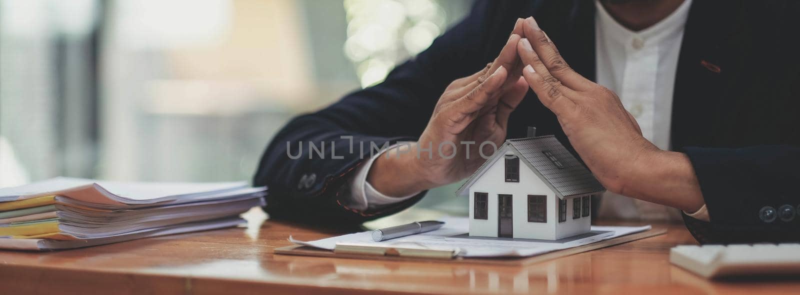 Real estate concept, businessman holding a house icon. House on Hand.Property insurance and security concept. Protecting gesture of female and symbol of house. by wichayada
