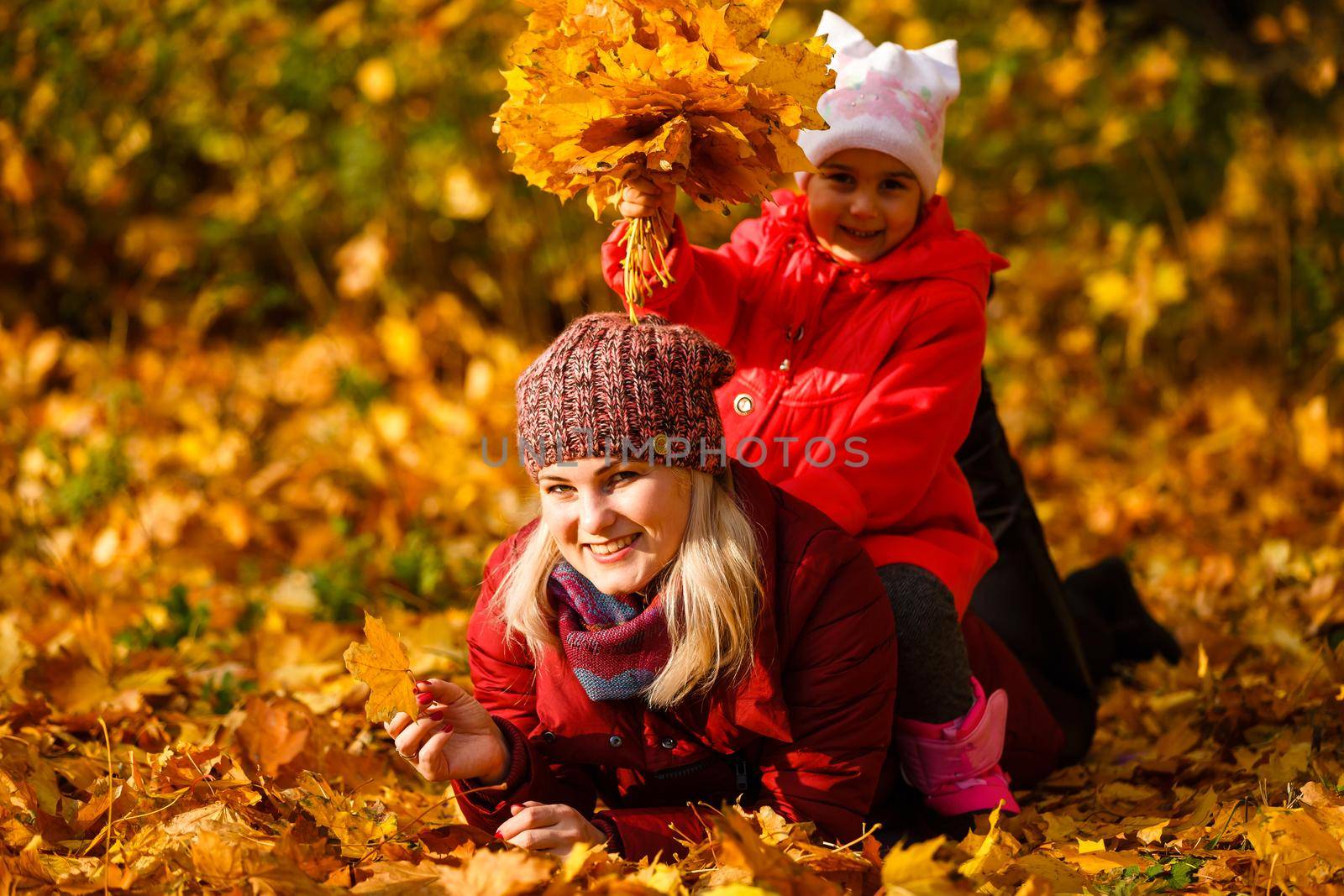 Young mother with her little daughter in an autumn park.