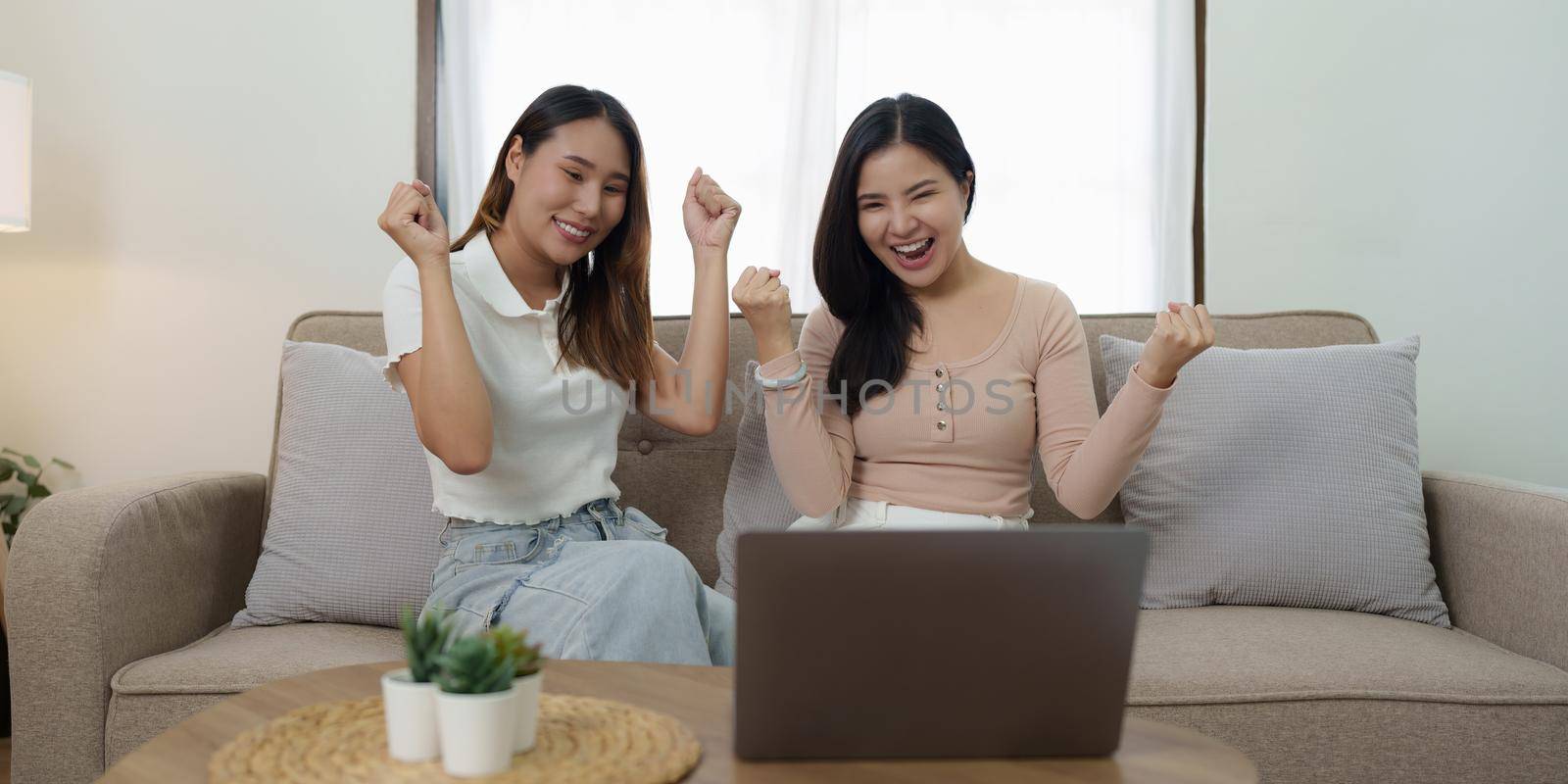 Two asian women having nice lively conversation in living room on sofa in cozy interior.