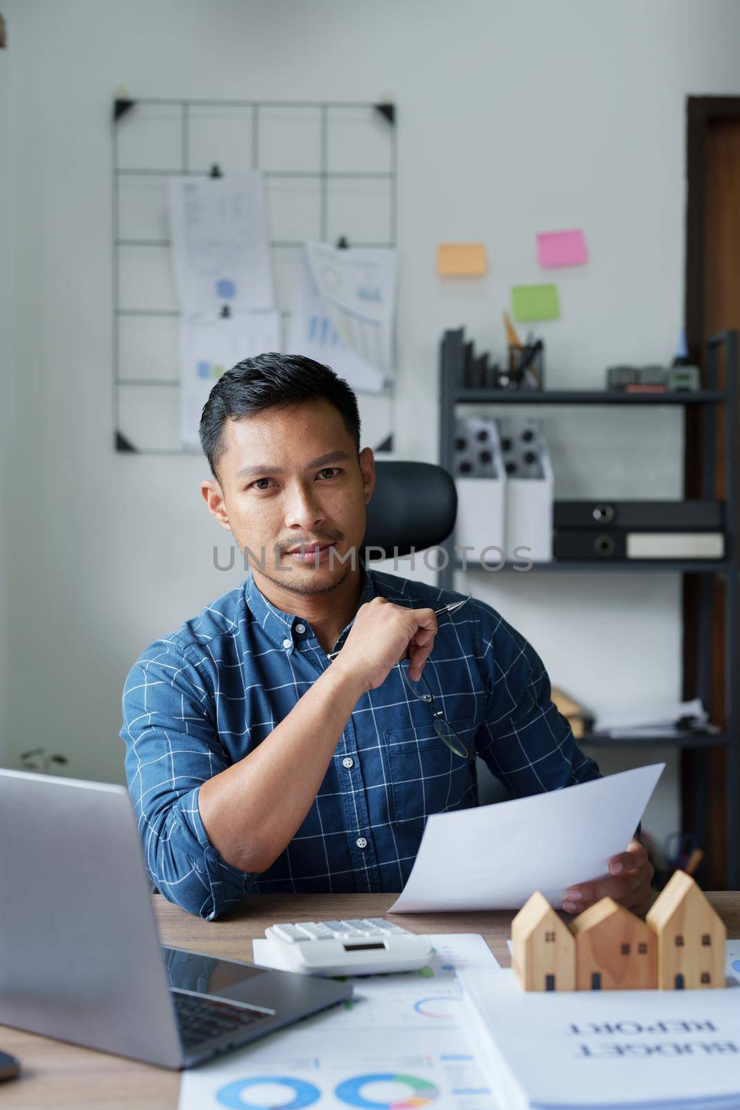 Entrepreneurs, business owners, accountants, real estate agents, A young man using a calculator to calculate his home budget to assess the risks of investing in real estate.