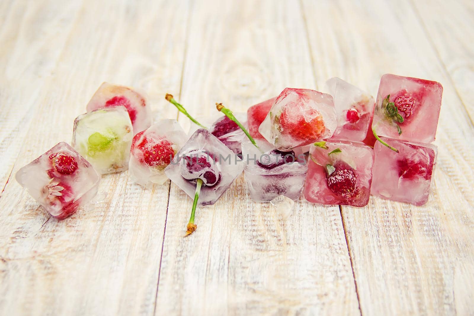 Berries frozen in ice cubes. Selective focus. by yanadjana