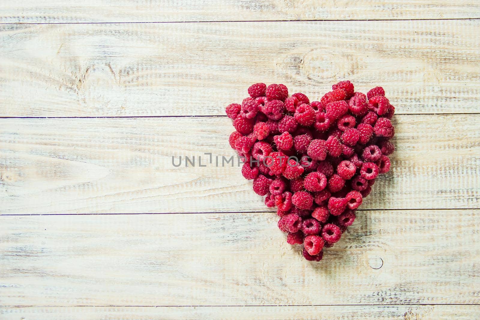 Raspberries are in the hands of a child in the form of a heart.