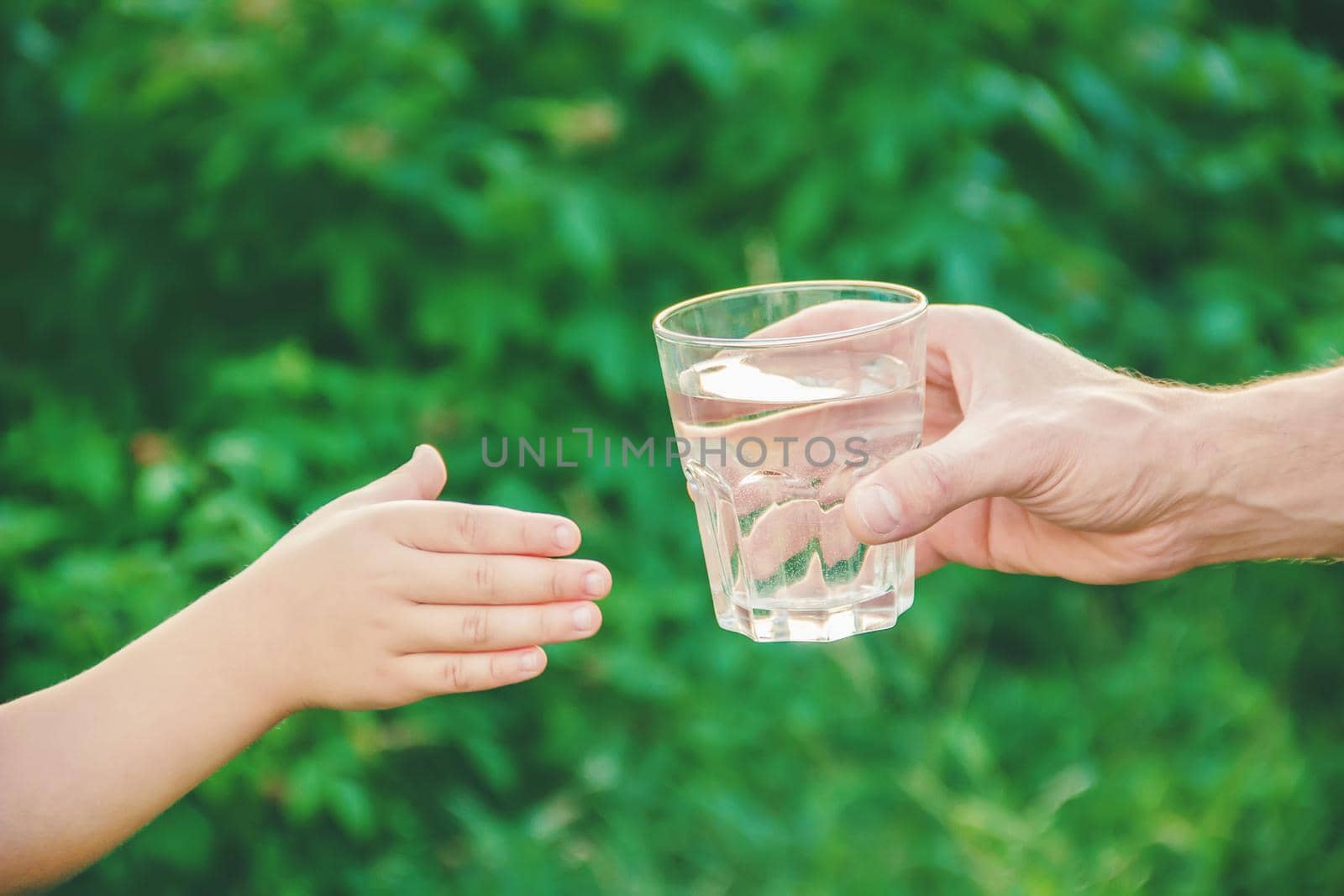 The father gives the child a glass of water. Selective focus. nature.