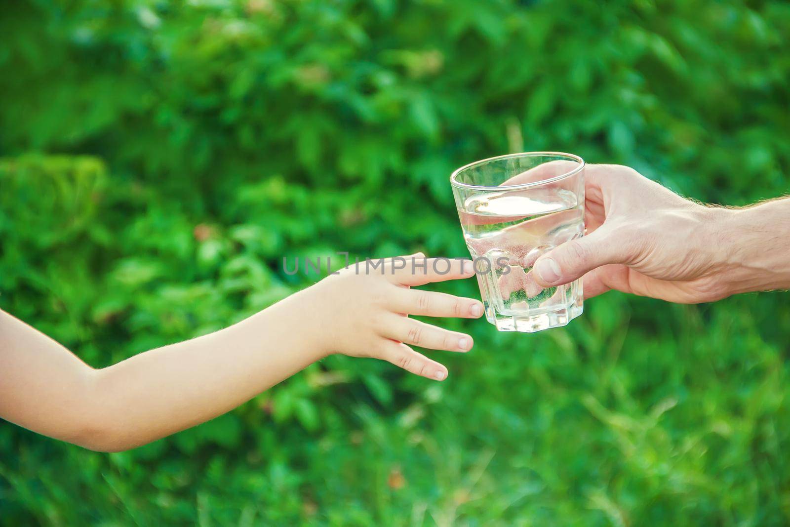 The father gives the child a glass of water. Selective focus.