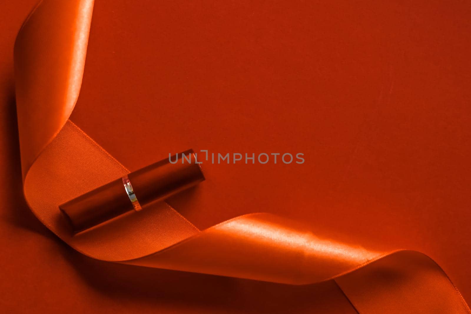 Cosmetic branding, glamour lip gloss and shopping sale concept - Luxury lipstick and silk ribbon on orange holiday background, make-up and cosmetics flatlay for beauty brand product design