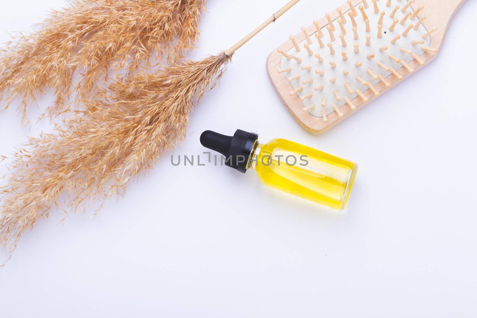 Oil for hair growth. Therapeutic oil to activate hair growth. Comb on white background. Hair care. Beauty and health.
