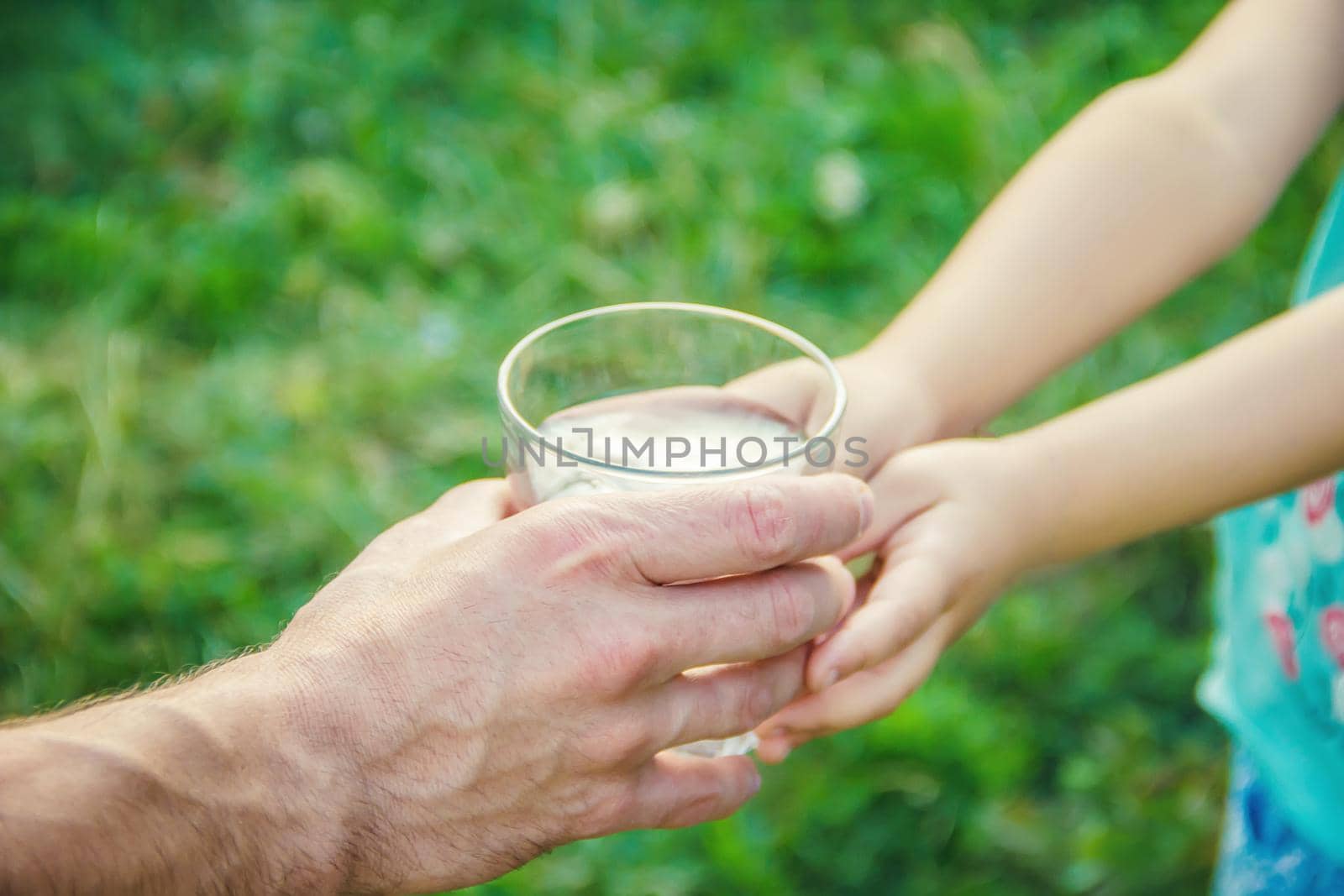 The father gives the child a glass of water. Selective focus. by yanadjana