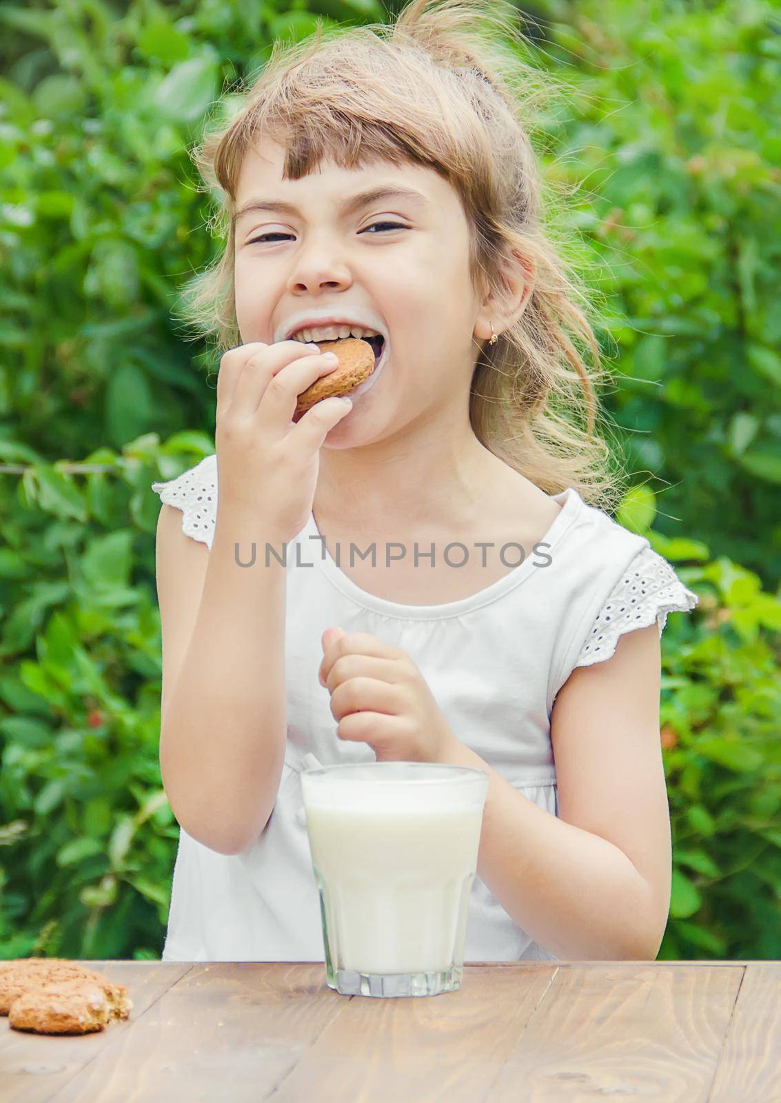 The child drinks milk and cookies. Selective focus.