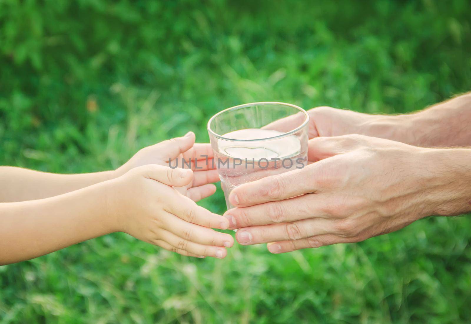 The father gives the child a glass of water. Selective focus.