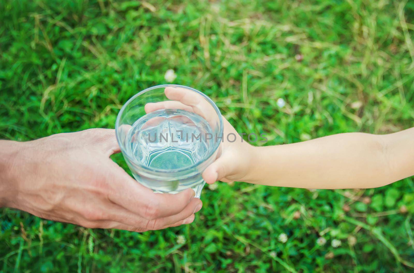 The father gives the child a glass of water. Selective focus. by yanadjana