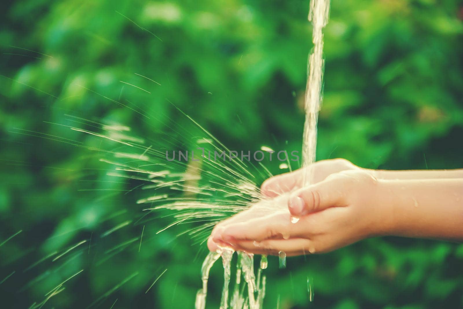 Water flows into the hands of the child. Selective focus. nature.