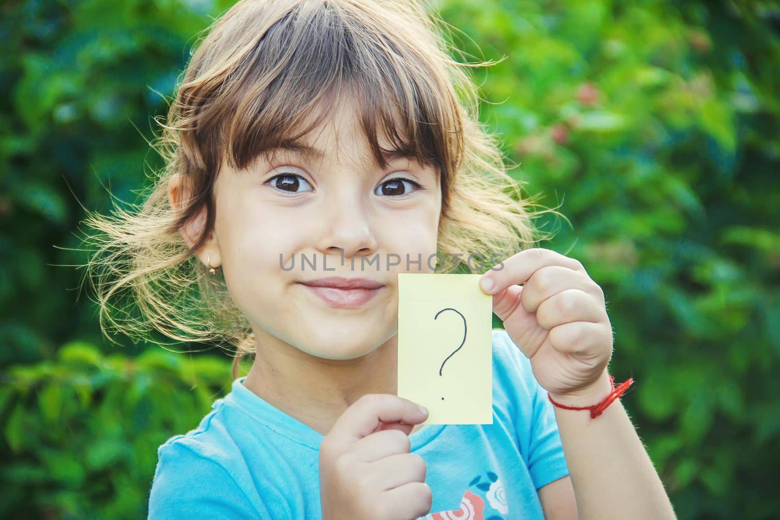 A child holding a sheet of paper with a question mark.