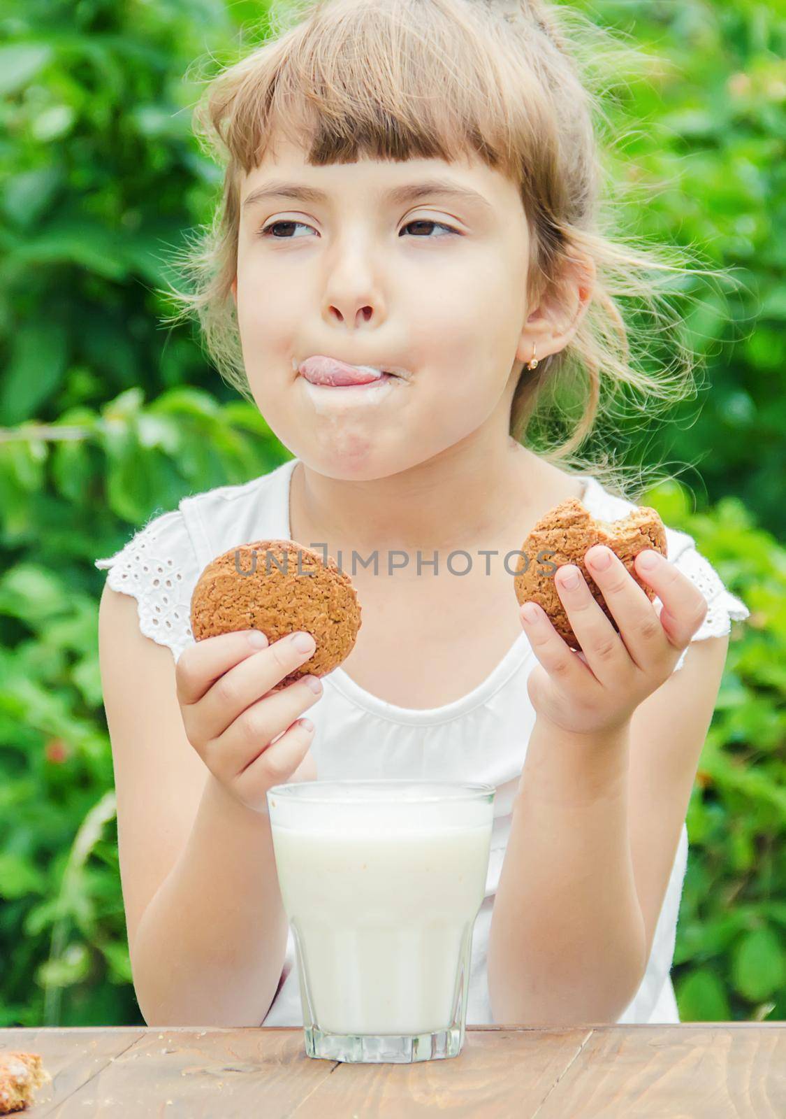 The child drinks milk and cookies. Selective focus.