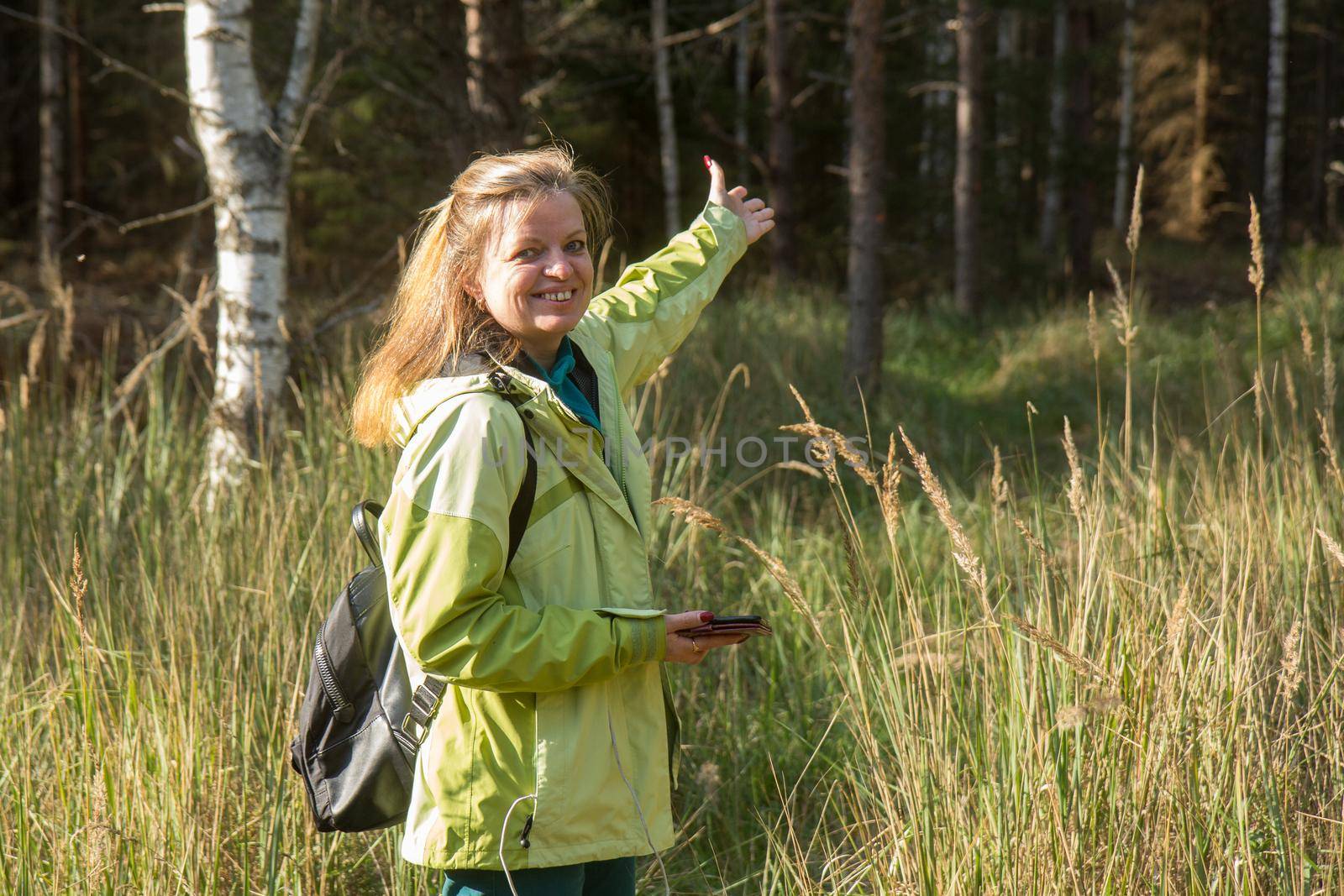 A woman with her mobile phone in the forest. Playing geocaching.