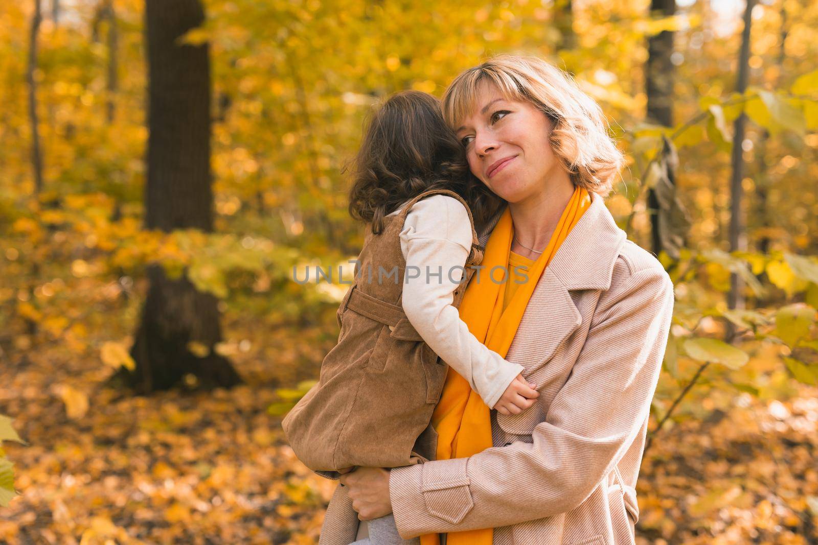 Mother with child in her arms against background of autumn nature. Family and season concept
