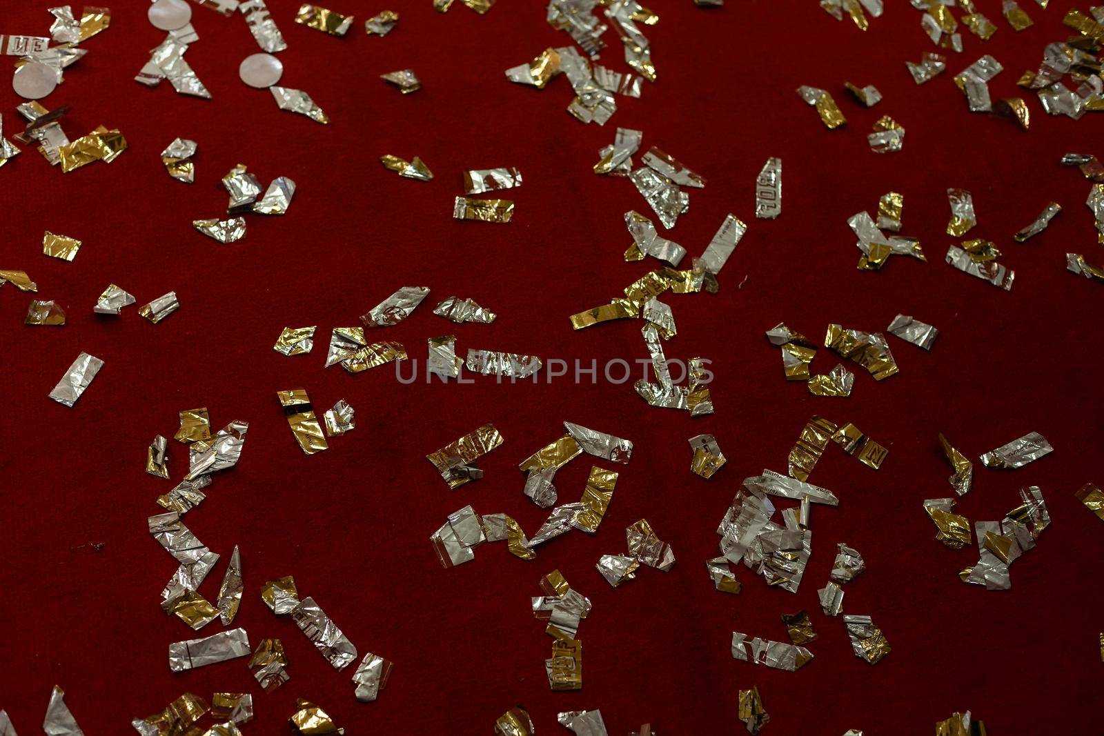Golden falling confetti on red glitter background. Christmas, festive, party or holiday background. Flat-lay, top view by Andelov13