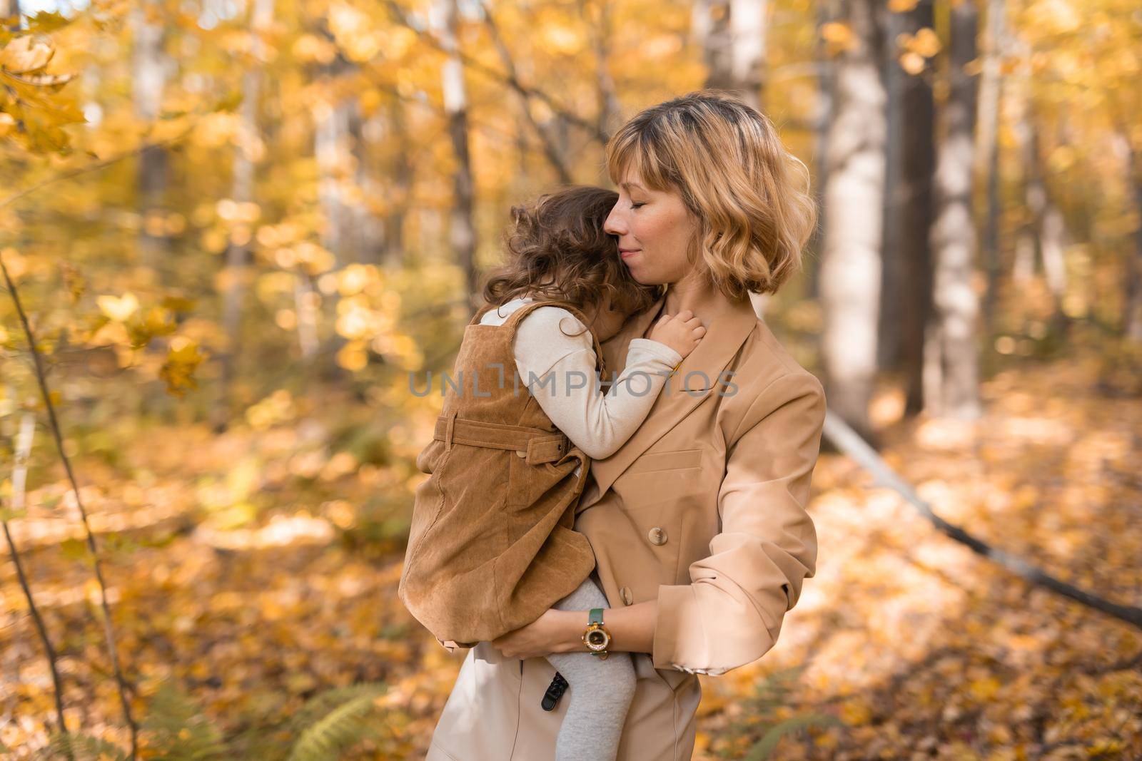 Beautiful lifestyle autumn photo mother and child walks evening in the park, warm sunlight