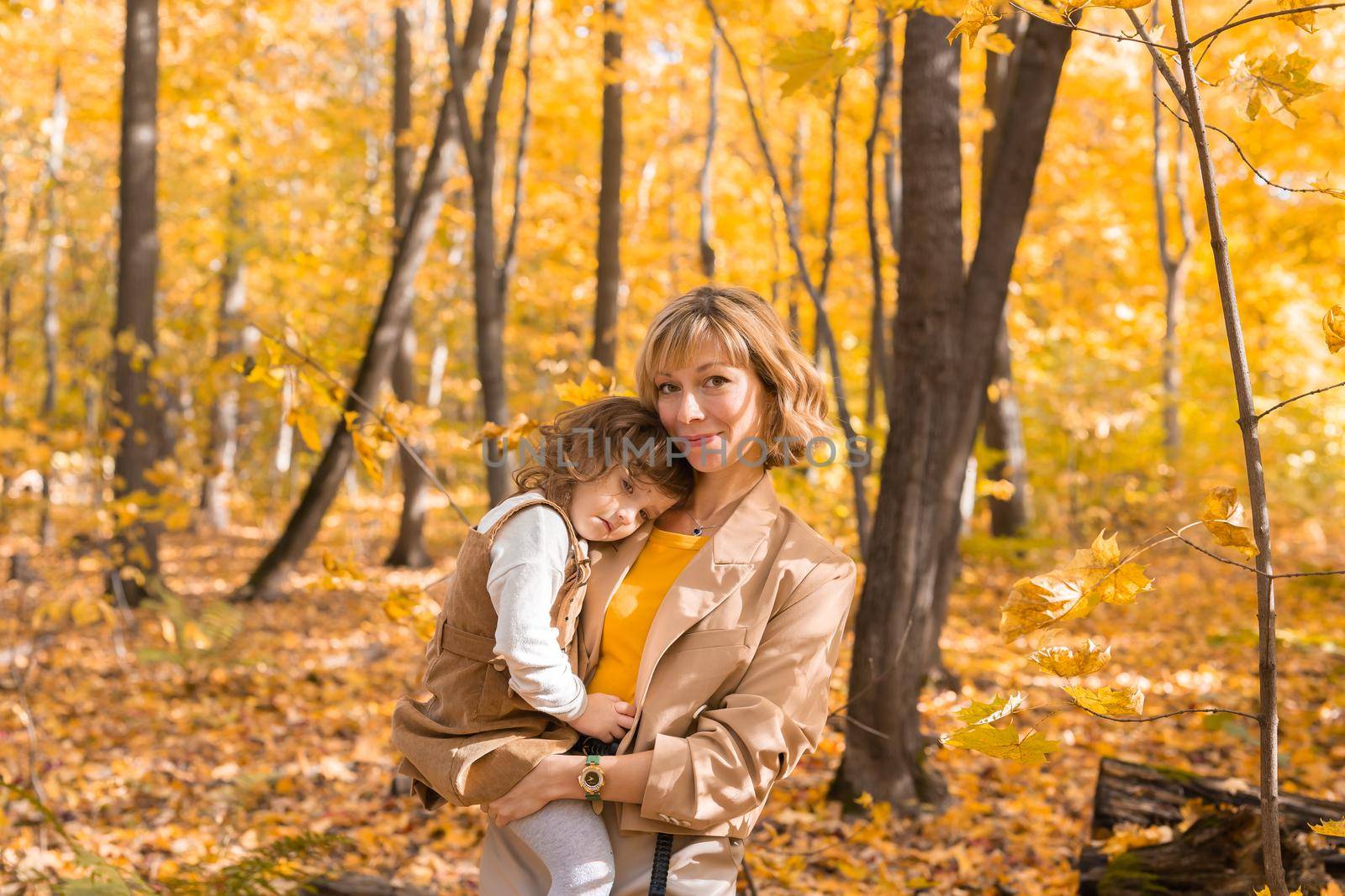 Beautiful lifestyle autumn photo mother and child walks evening in the park, warm sunlight