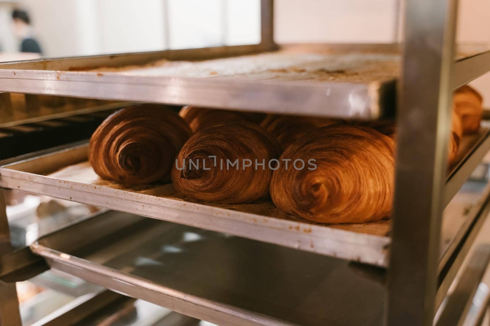 Production of delicious buns. Family bakery. Hot croissants on a metal tray. Fresh bakery. Rack with baked croissants.