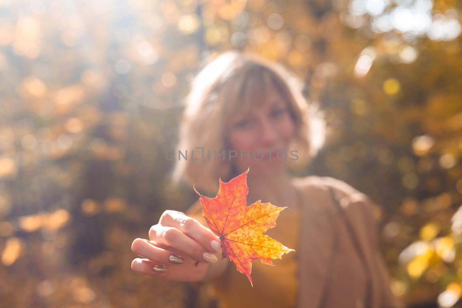 Woman holding yellow and orange autumn maple leaf. Fall season by Satura86