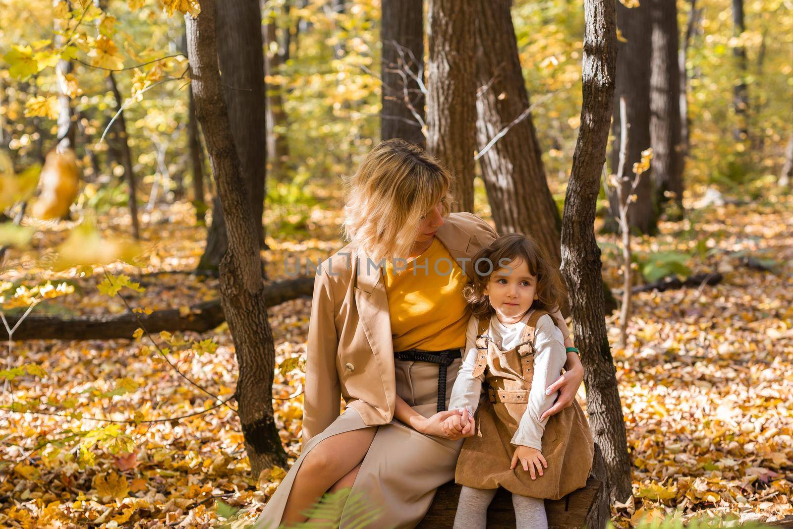 Beautiful lifestyle autumn photo mother and child walks evening in the park, warm sunlight