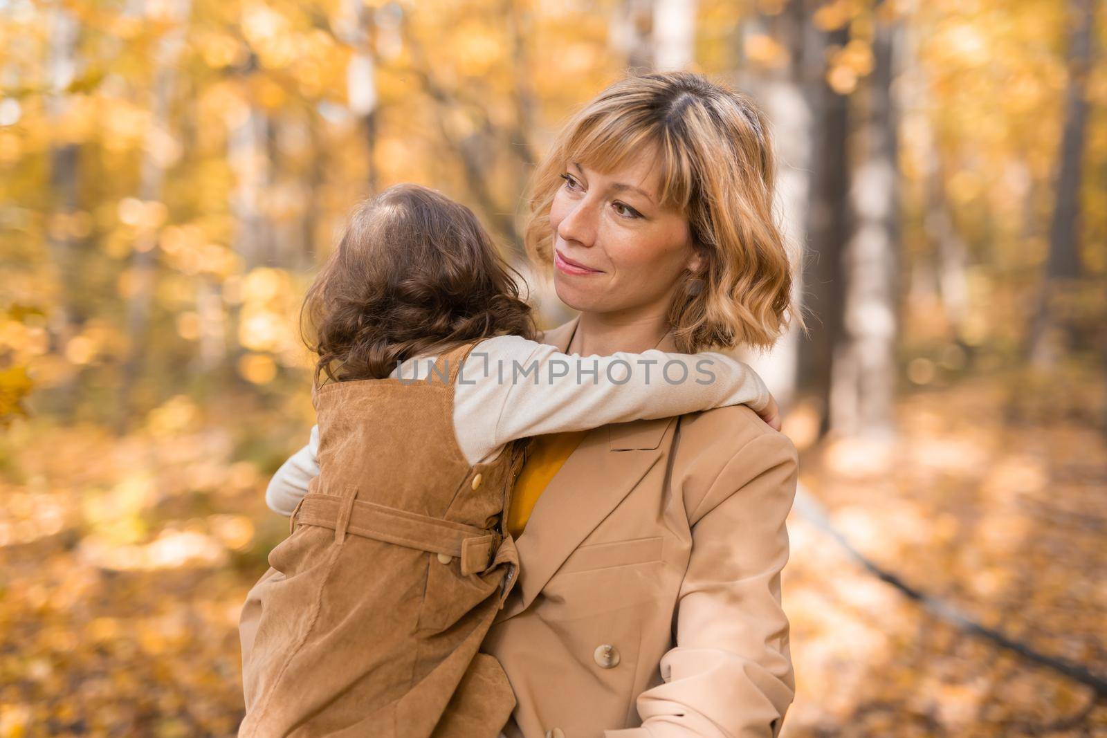 Mother with child in her arms against background of autumn nature. Family and season concept. by Satura86